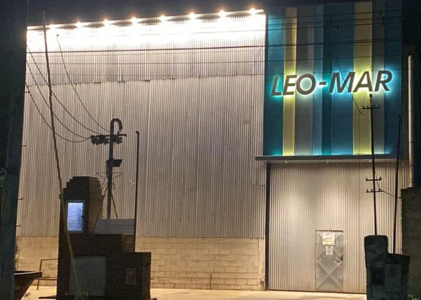 Frente del taller de Leo-Mar sobre la ruta 178, de noche, con el cartel iluminado